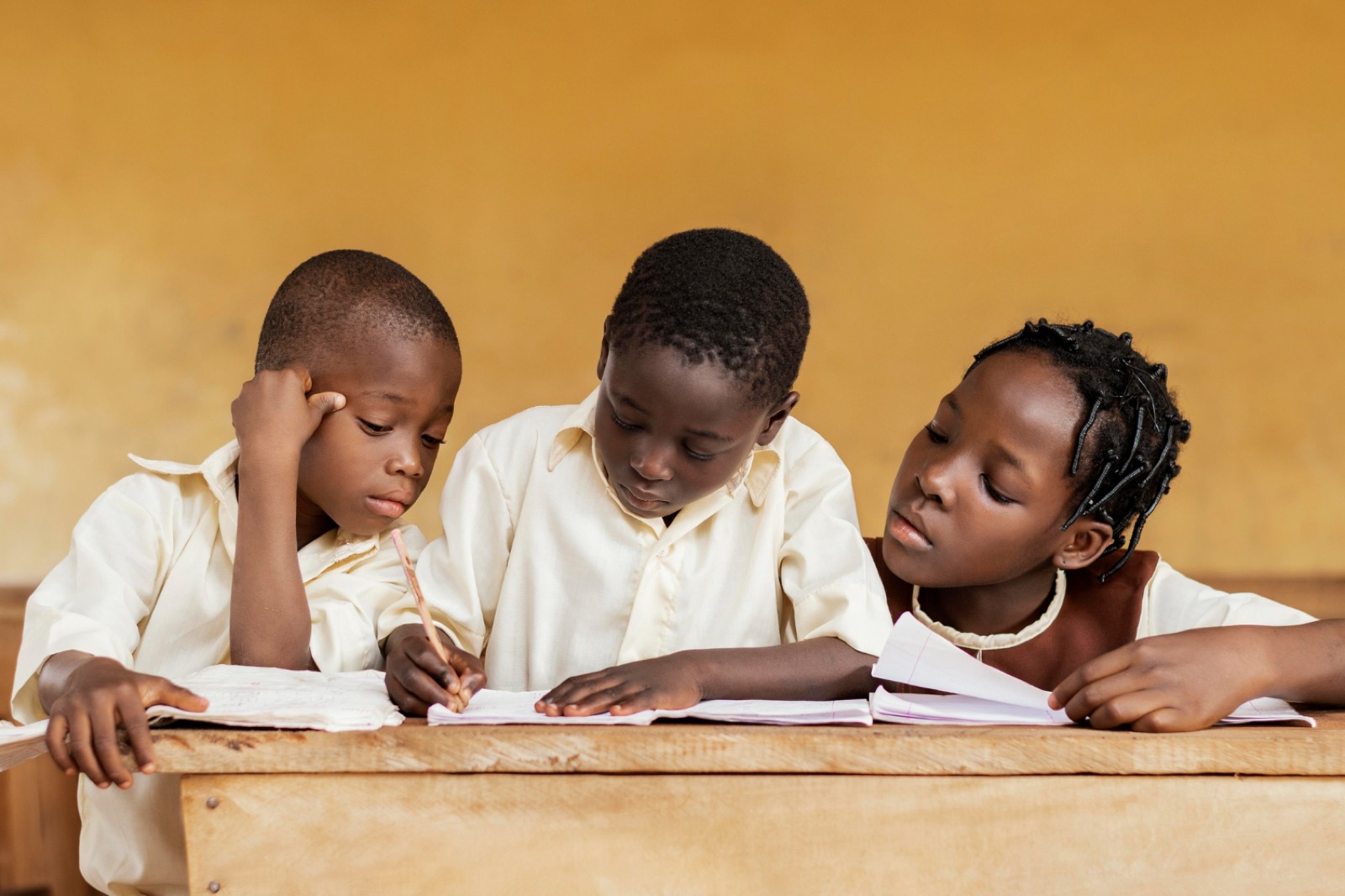 Three pupils gathered around a shared book